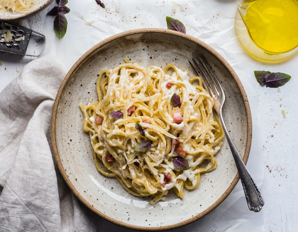 Een rustiek bord met spaghetti carbonara op een mooi opgemaakte tafel
